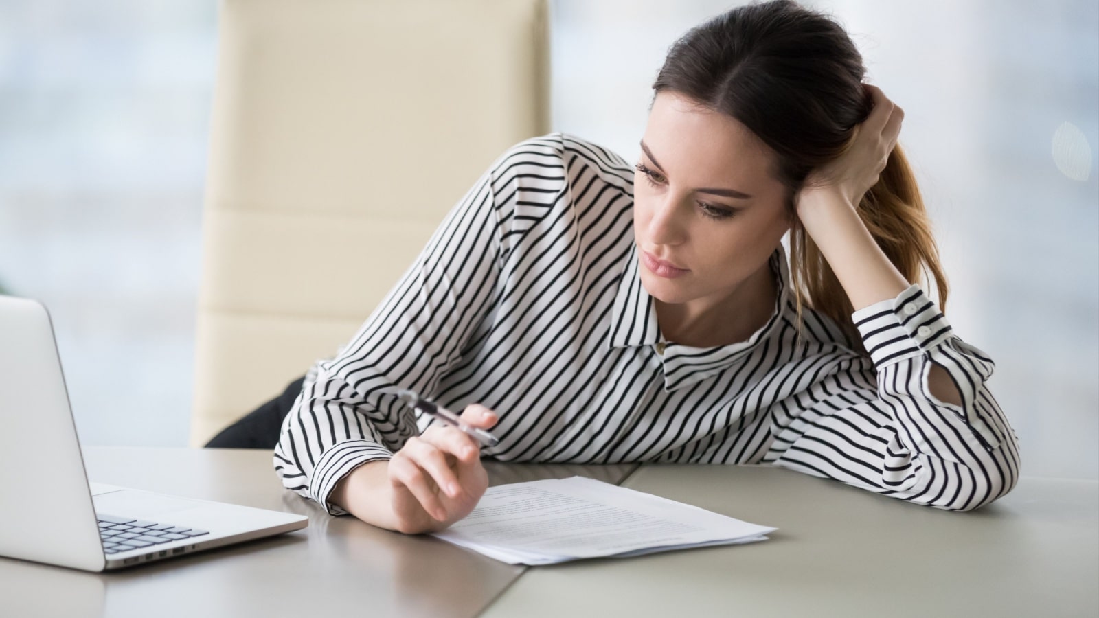 A secretary looks bored without the internet as she stares at papers on a desk.