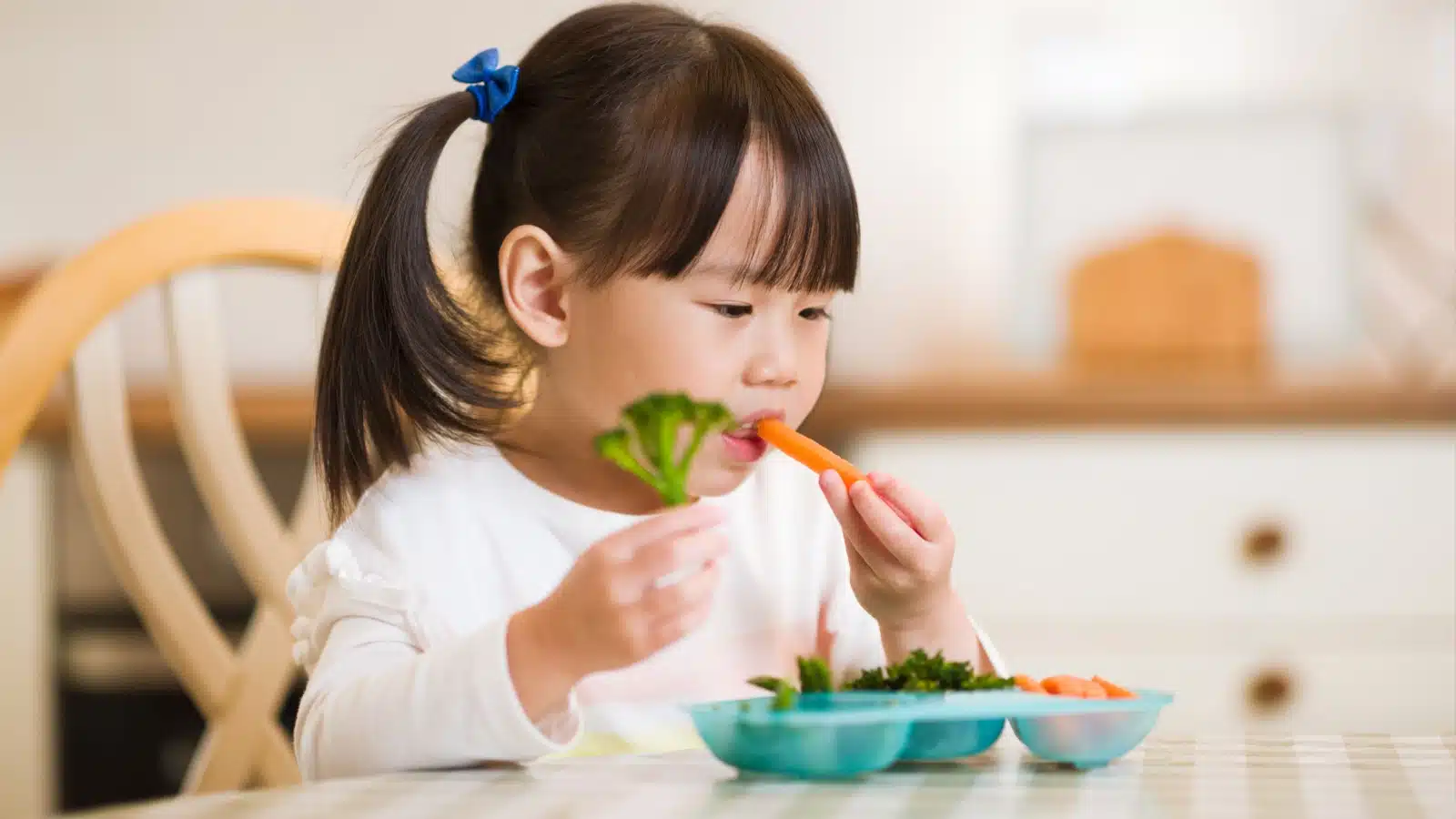 A little girl eats healthy vegetables for lunch.