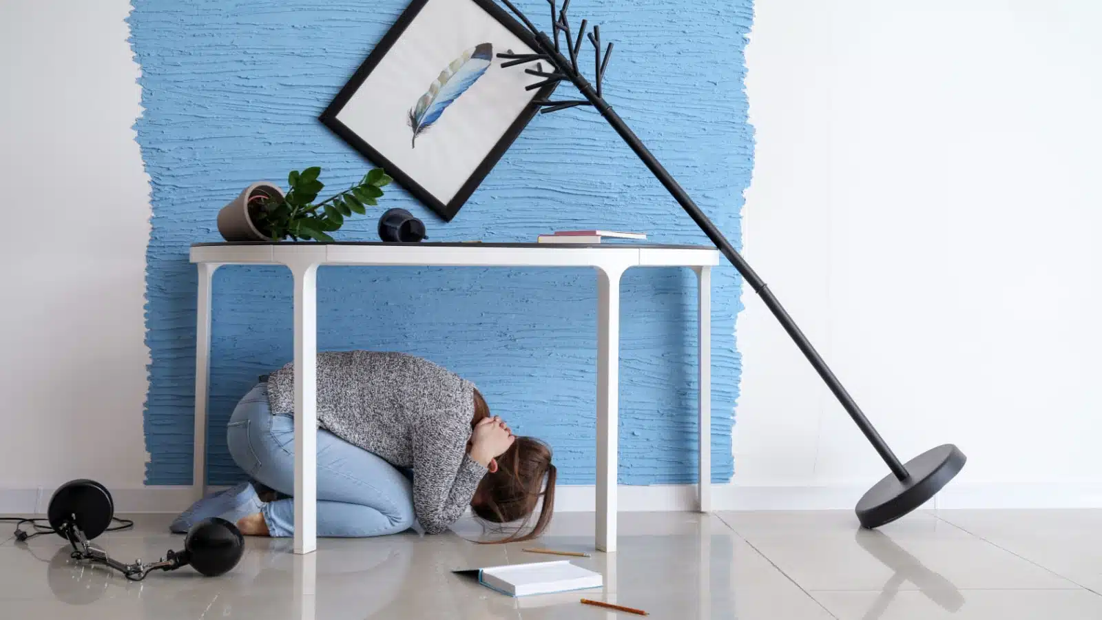 A woman hiding under a table during a small earthquake.