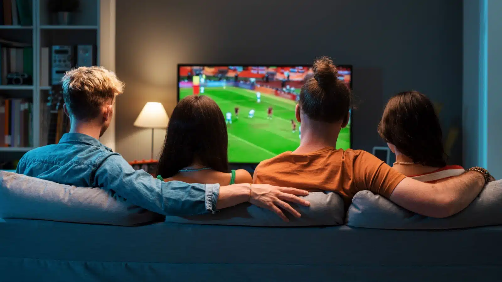 Two young couples watch television together on the couch.
