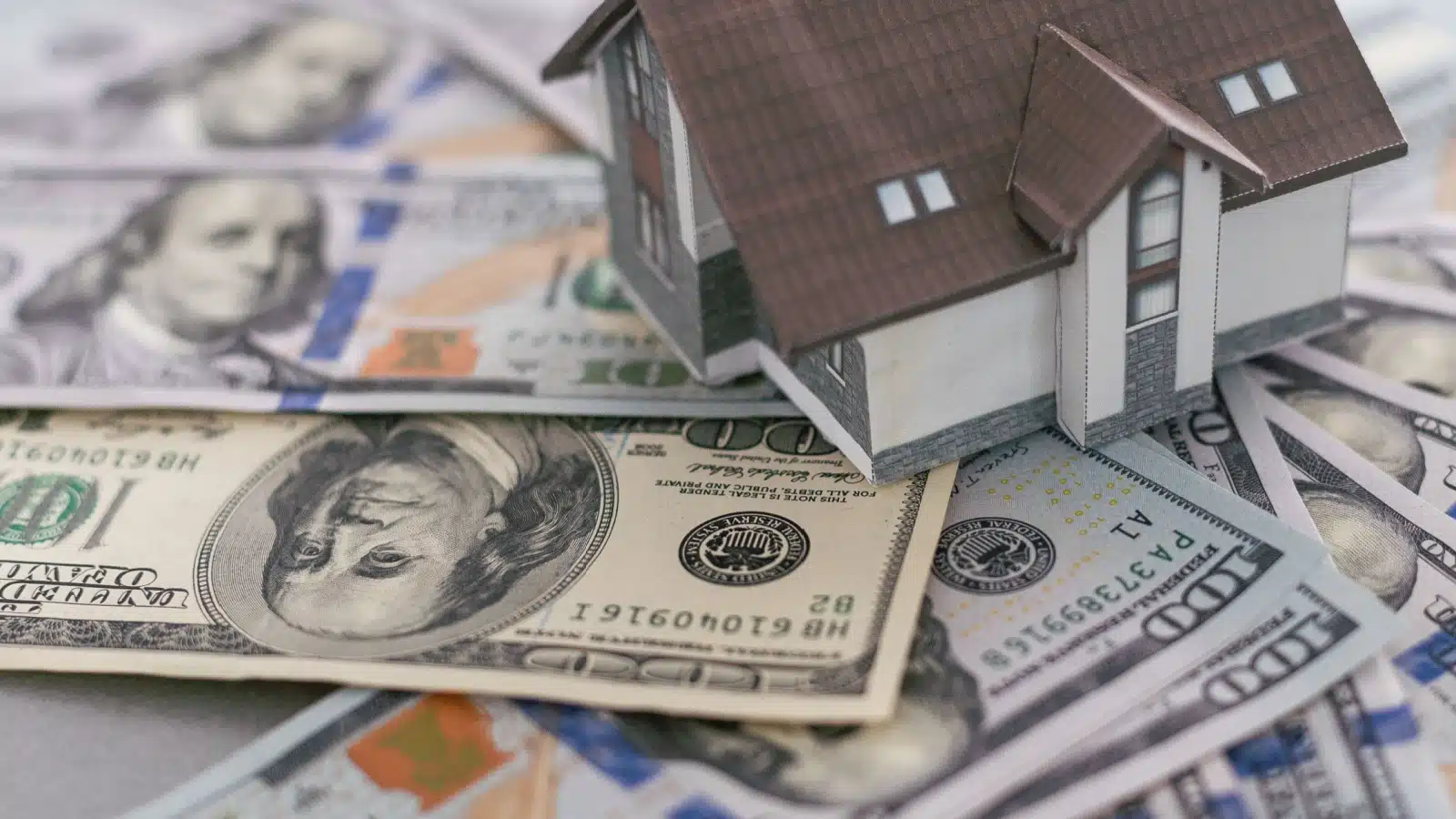 A model home sitting on a pile of cash to represent home equity.