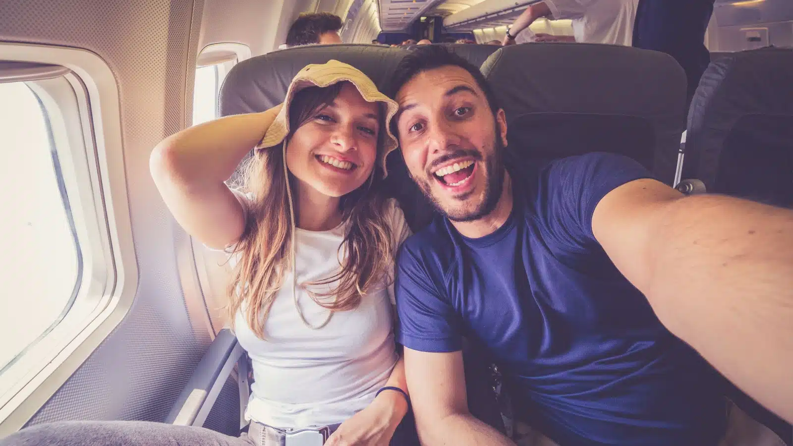 Happy couple taking a selfie in an airplane to represent travel tips. 