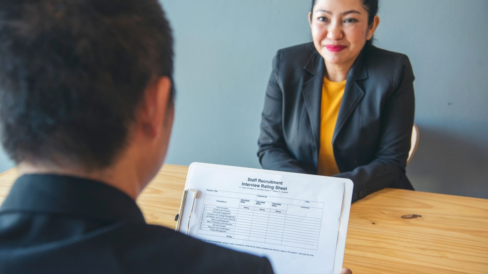 A nervous woman in a job interview with the HR representative who is reviewing her resume.