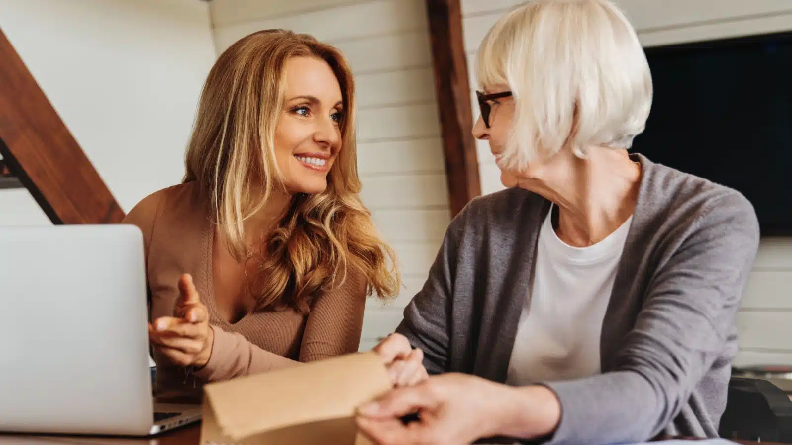 A mom with her adult daughter at a computer. It looks like the mom is helping financially.