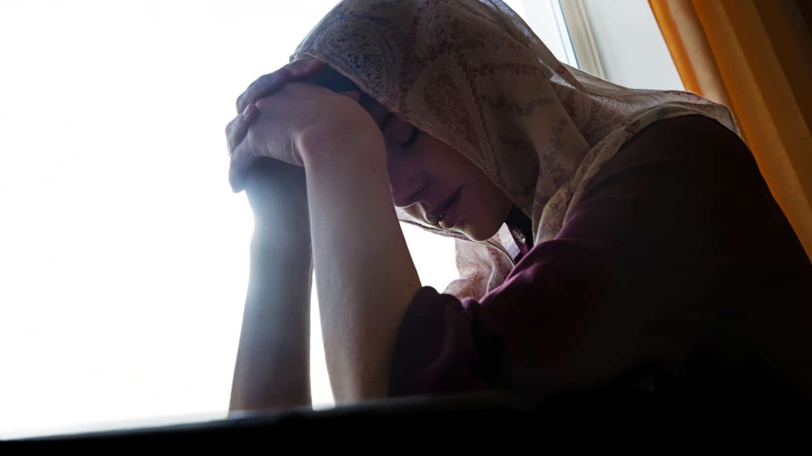 A sad, pious women sitting by the window to represent how Pascal's Wager is bad for women.