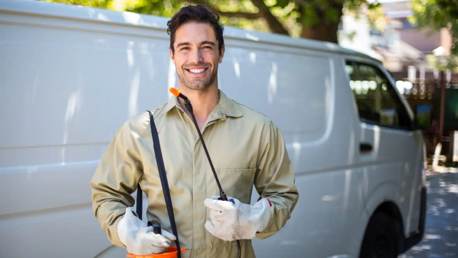 A smiling pest control worker standing in front of his van.