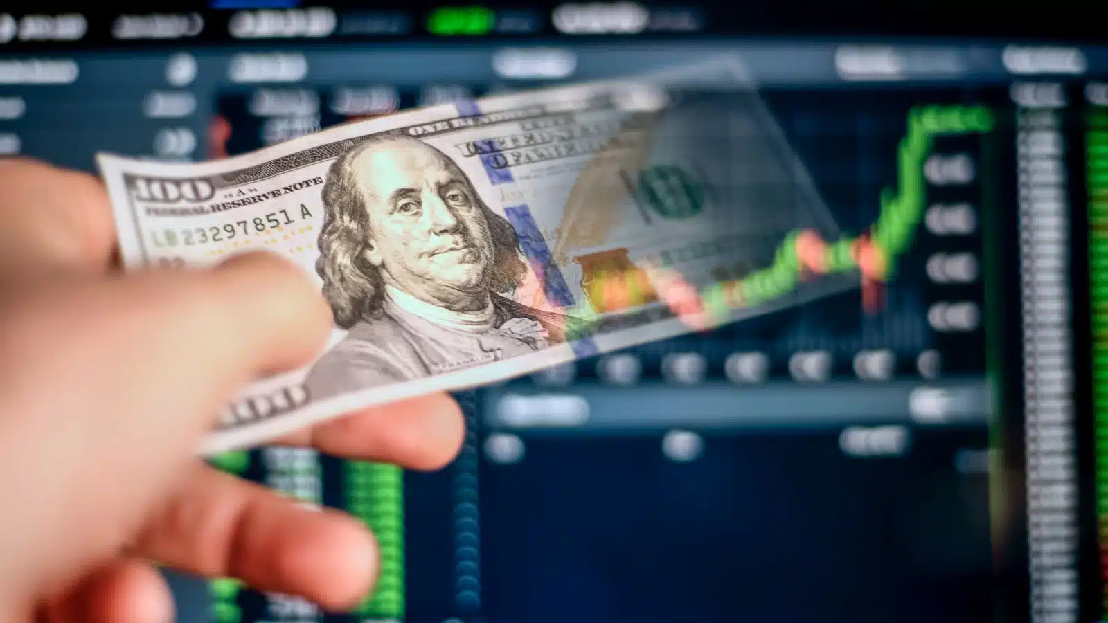 Concept art representing realized gains in investing. A hand pulls a $100 bill out of his computer screen, which has a stock chart on it. The image represents taking profits from an investment.