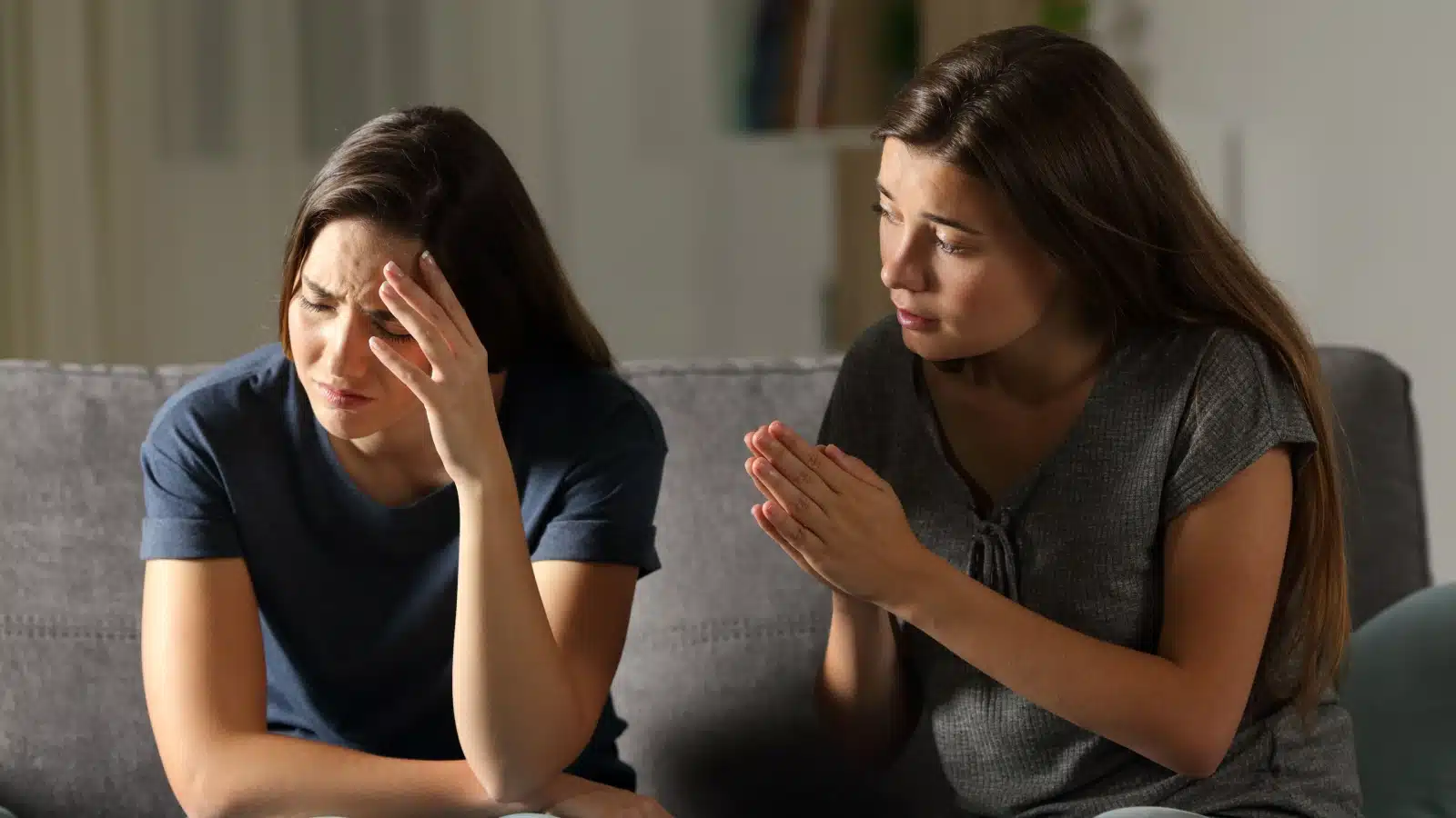 A girl begs her friend for help. The friend looks sad and feels bad.