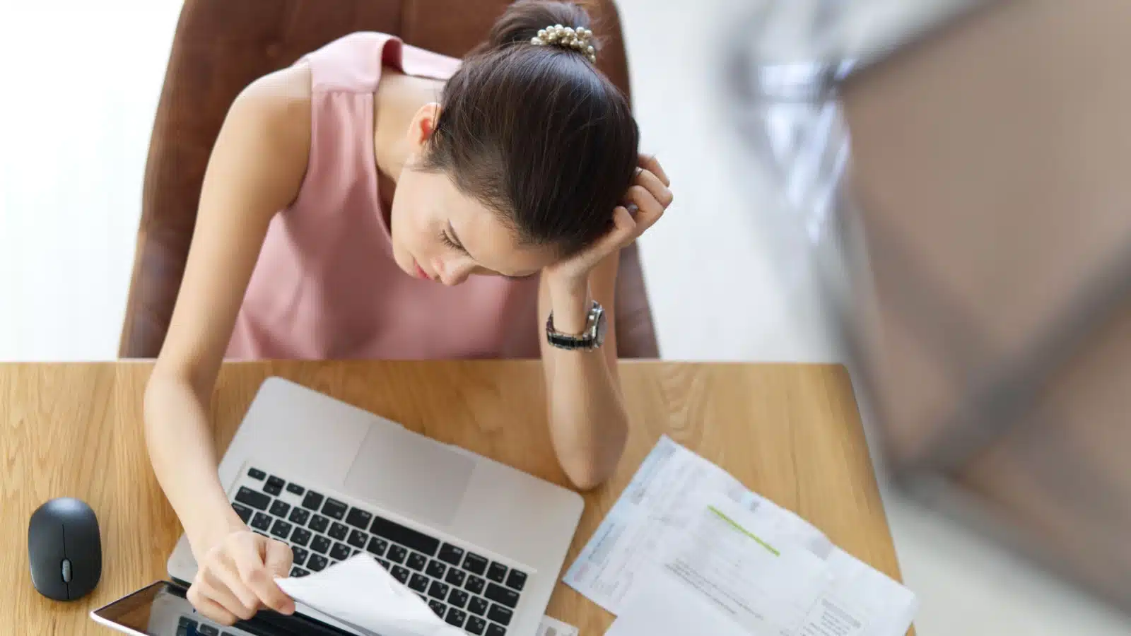 A sad woman looks at her bills because she has no money, to represent a financial mistake. 