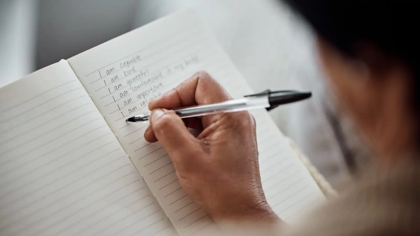 A woman writes affirmations in her journal.