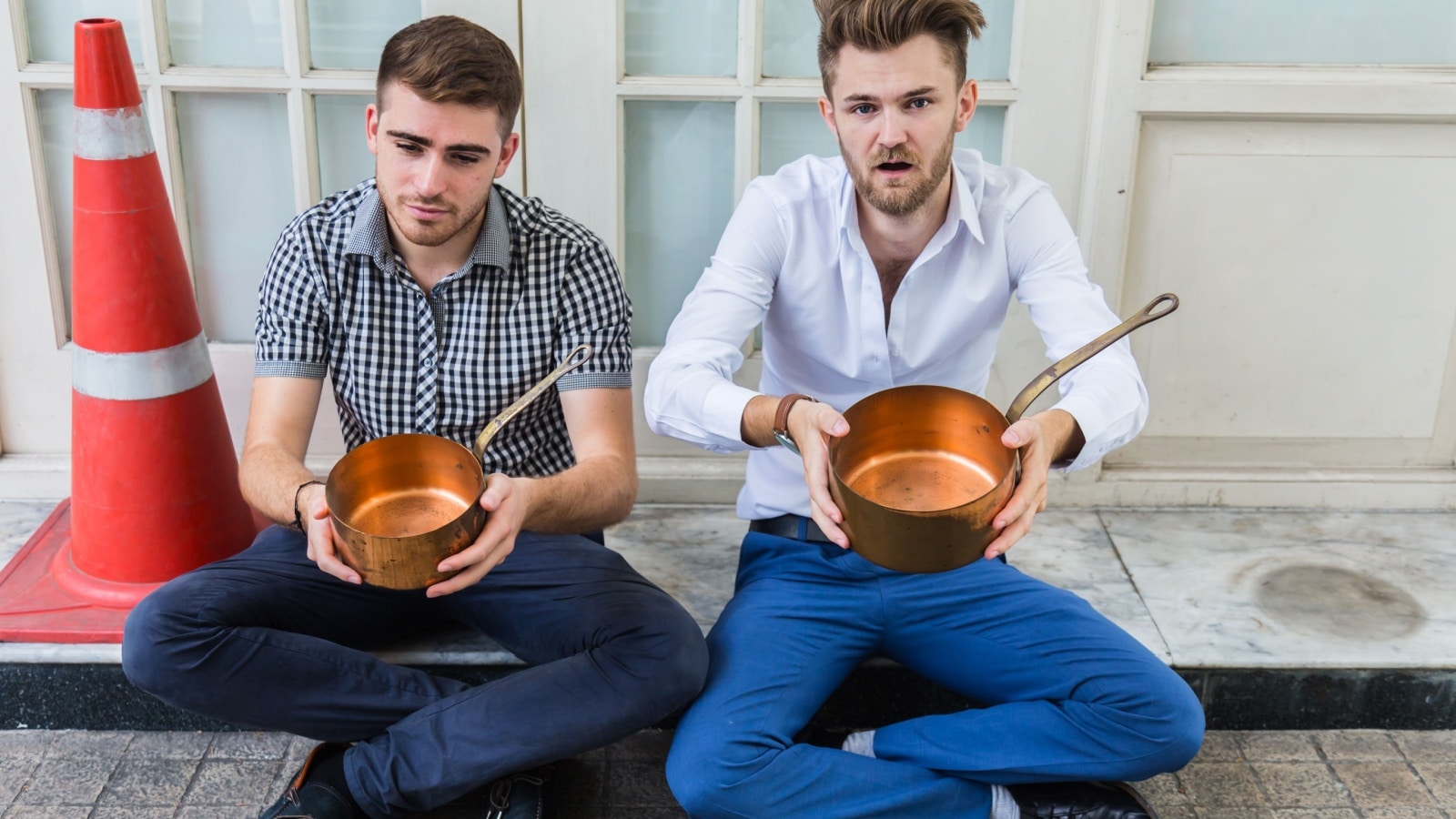 Two young men dressed well begging with pots to represent beg packing.