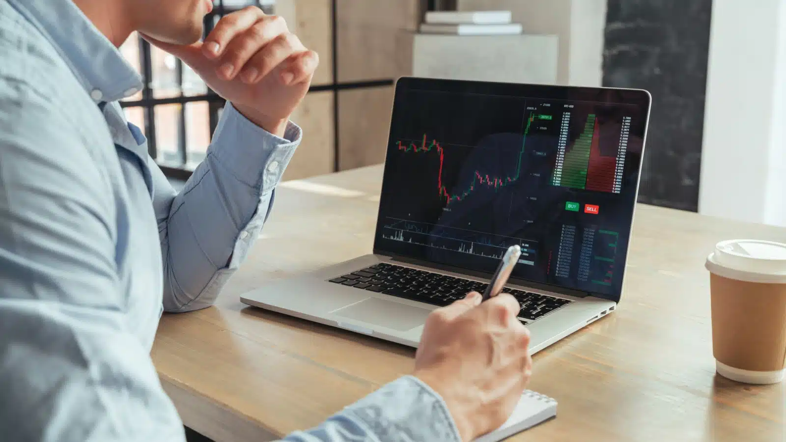 A man sits in front of a computer, tracking a stock as it rises, to represent unrealized gains.