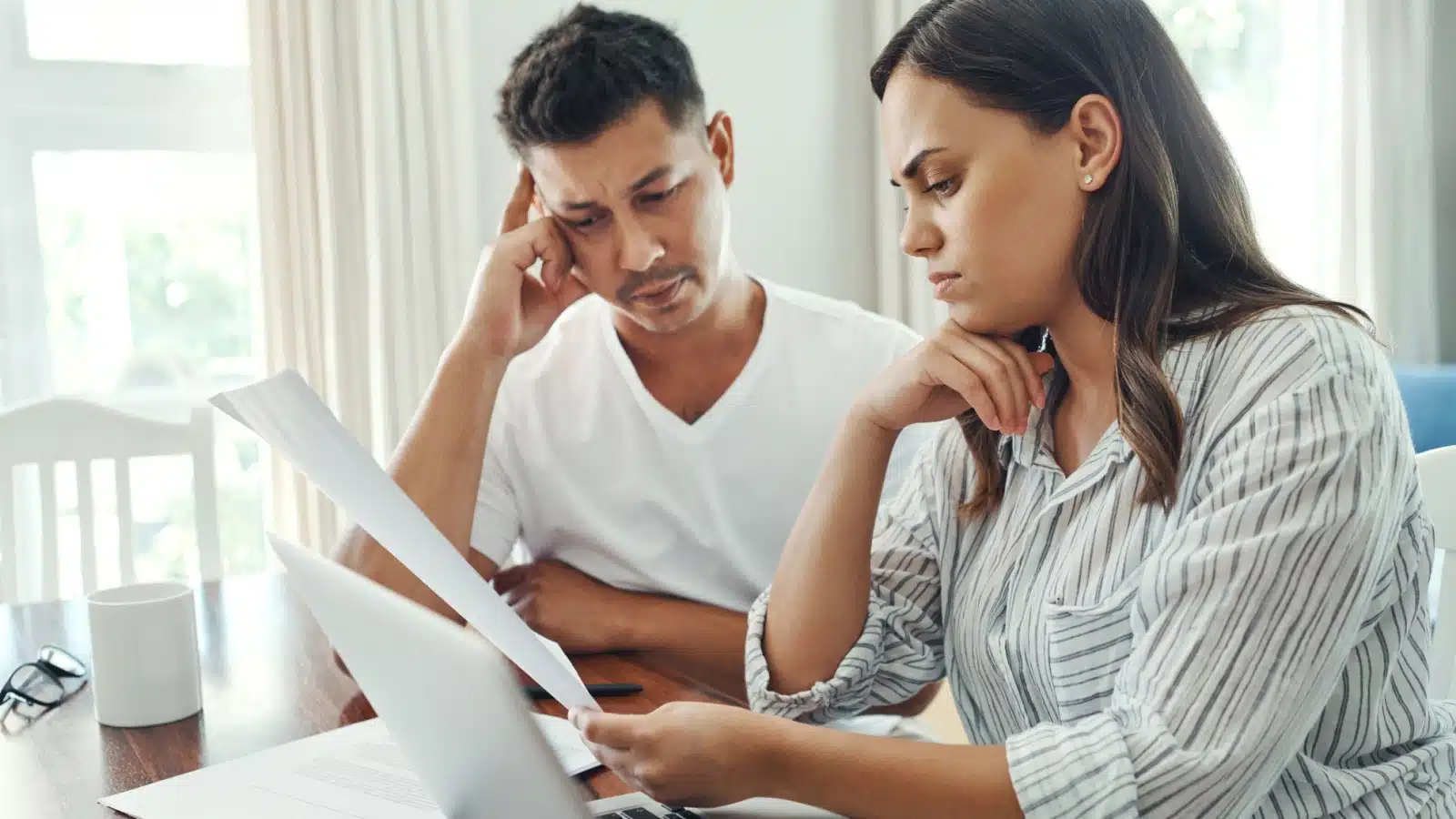 A couple looks at investment paperwork, unsure of what to do.