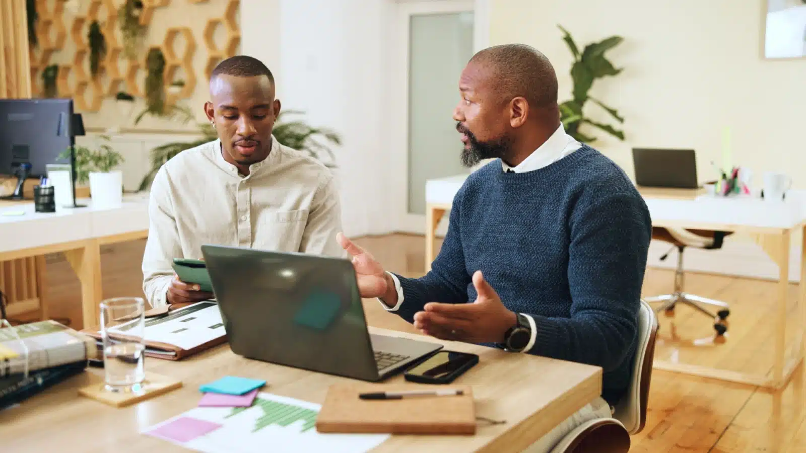 An older worker coaches his younger colleague.
