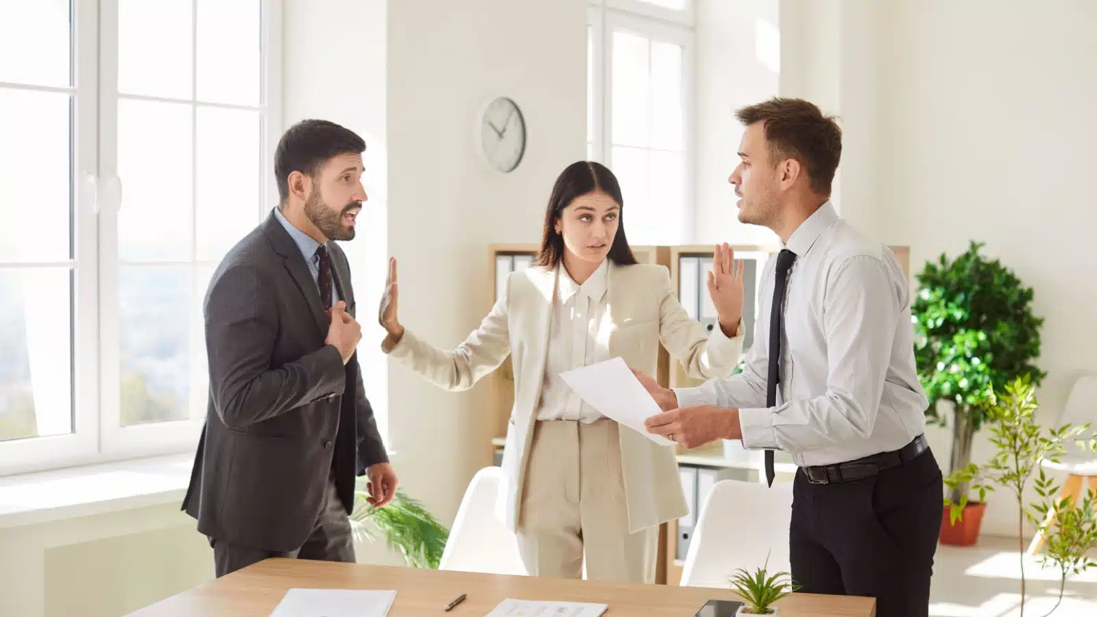 A woman breaks up an argument between her colleagues to represent the conflict management leadership skill.