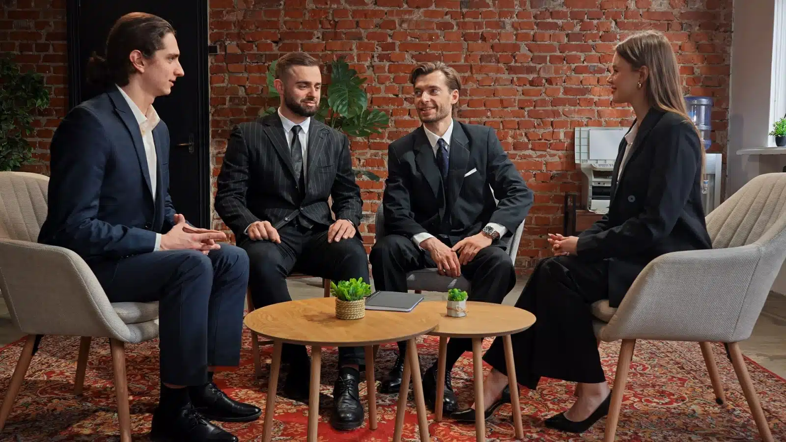 A group of four business leaders have a discussion around a table.