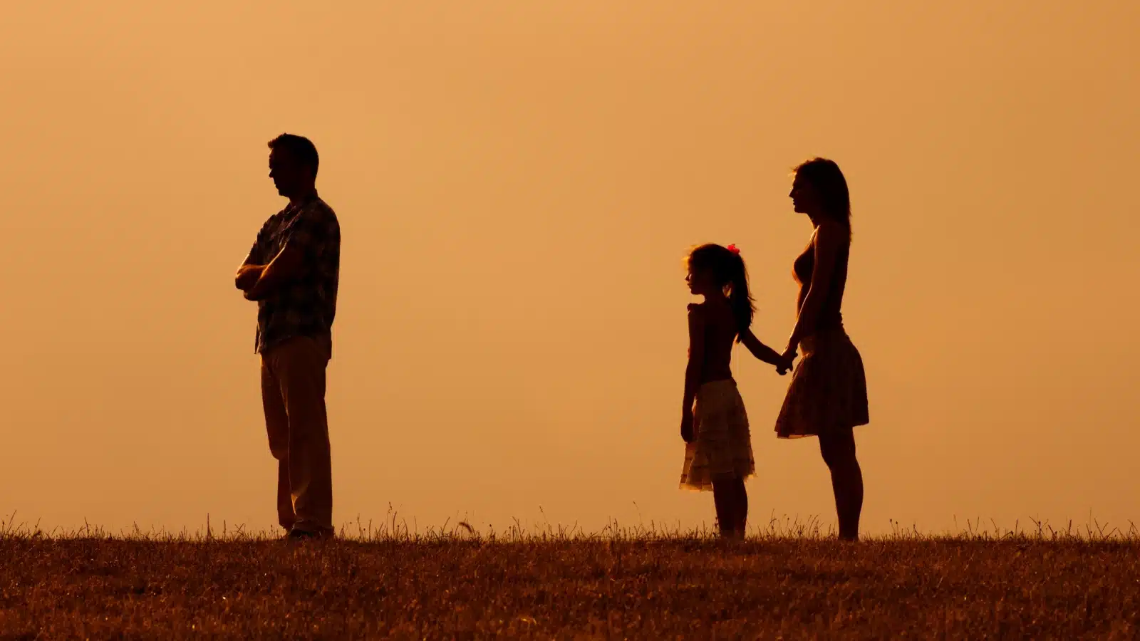 Silhouette of a man standing facing away from his wife and daughter, to represent a man who wants to leave.