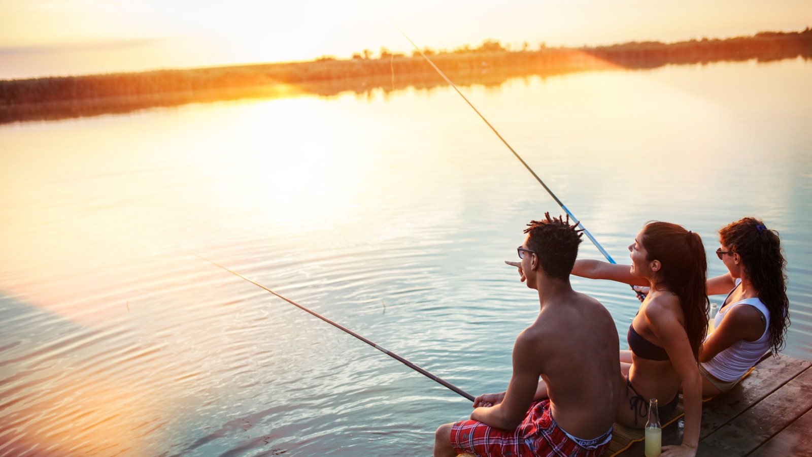 Three friends fishing at a lake.