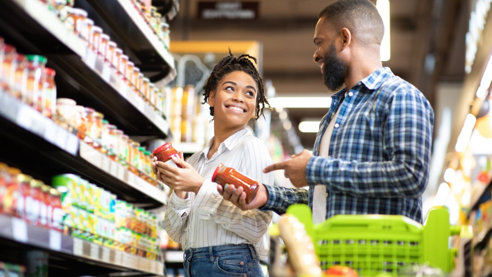 A happy couple comparing products at the grocery store to represent generic foods vs name brand products at the grocery store.