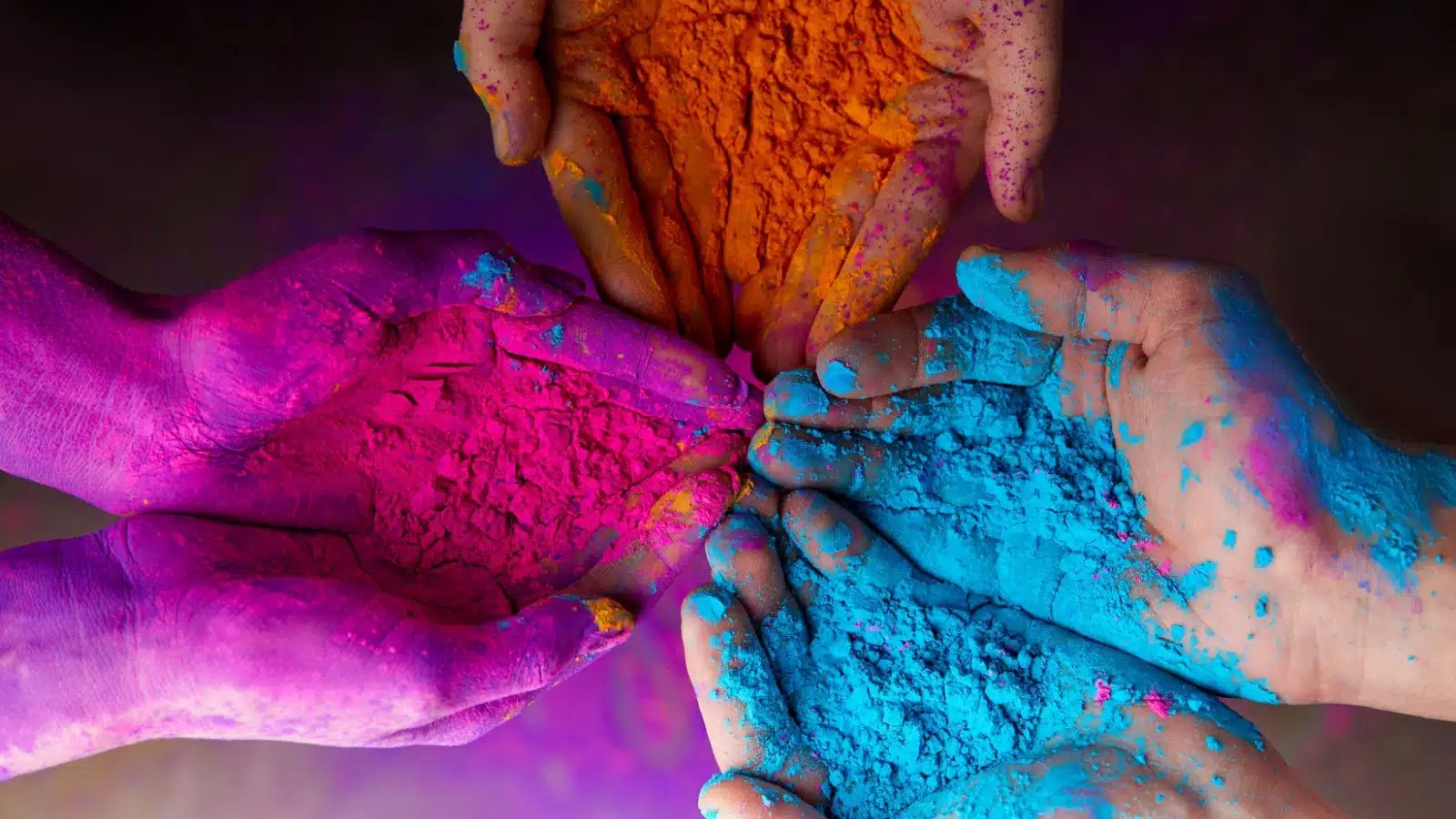 Close up of hands holding brightly colored powders used in Holi celebrations.