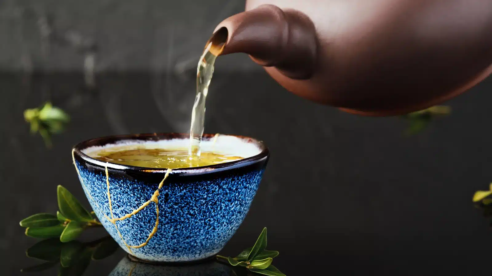 Hot tea being poured into a cup repaired with Kintsugi.