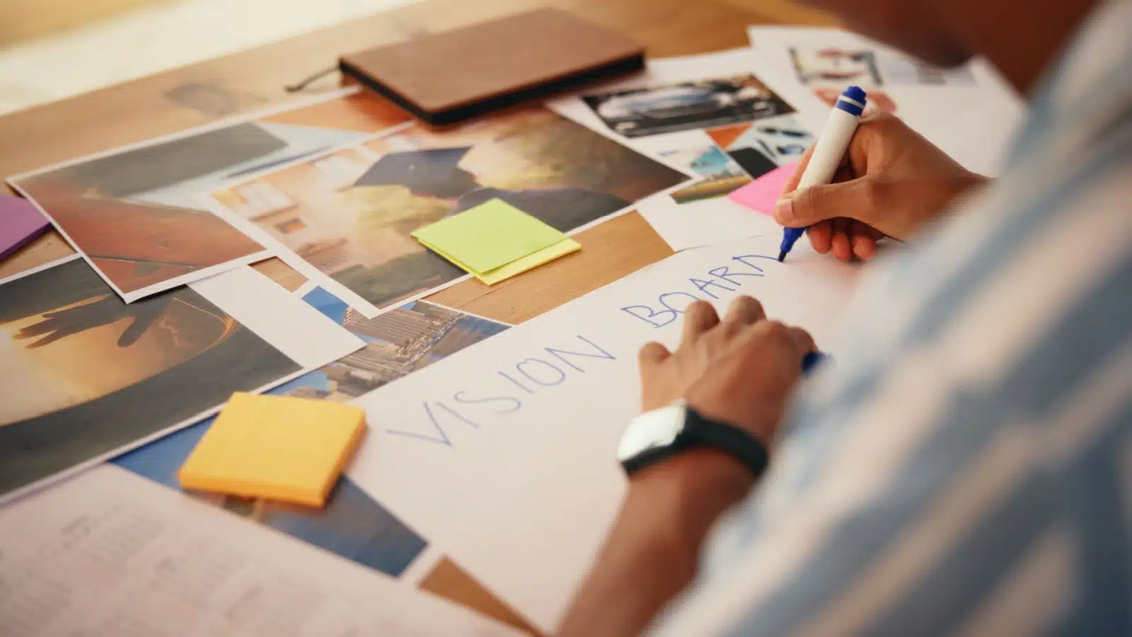 A woman making a vision board with all the supplies on a table.