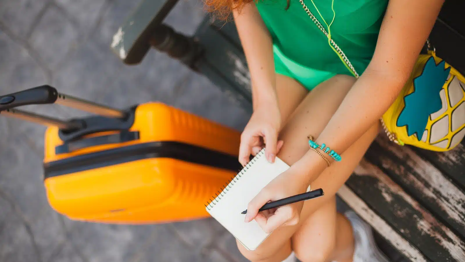 A woman uses a pocket notebook to record her thoughts while traveling.