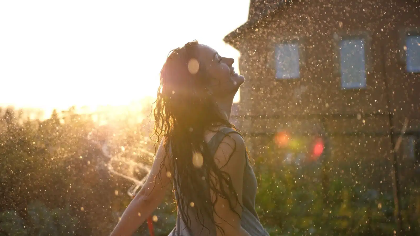 A happy woman playing outside in the rain.