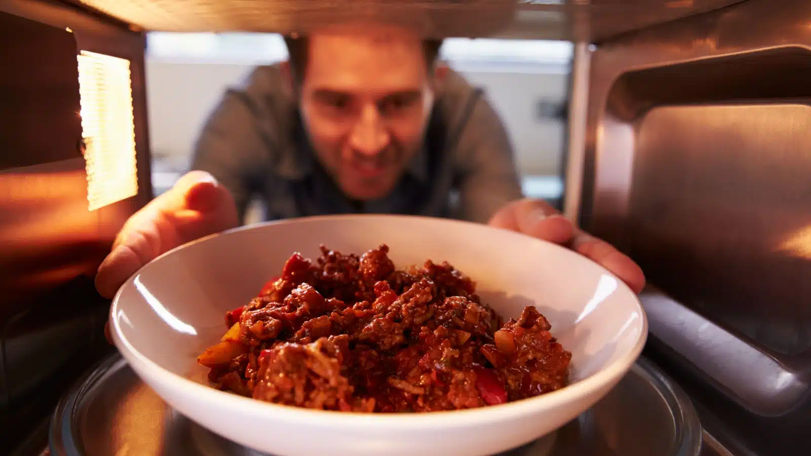 A man reheating food in the microwave.