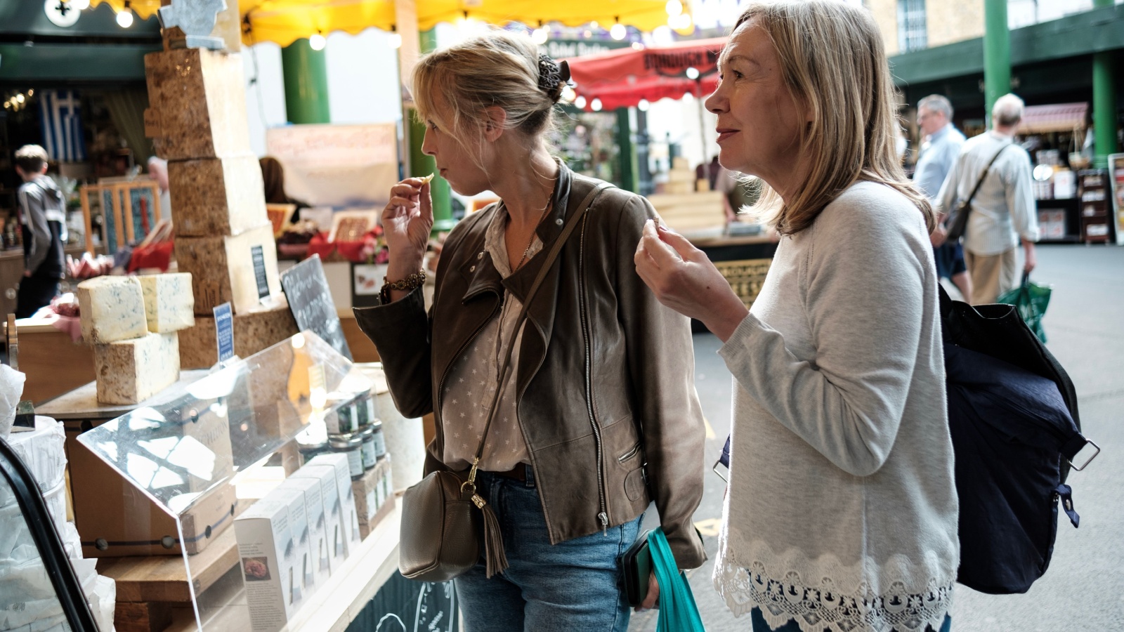 Friends sampling cheese at an outdoor market.