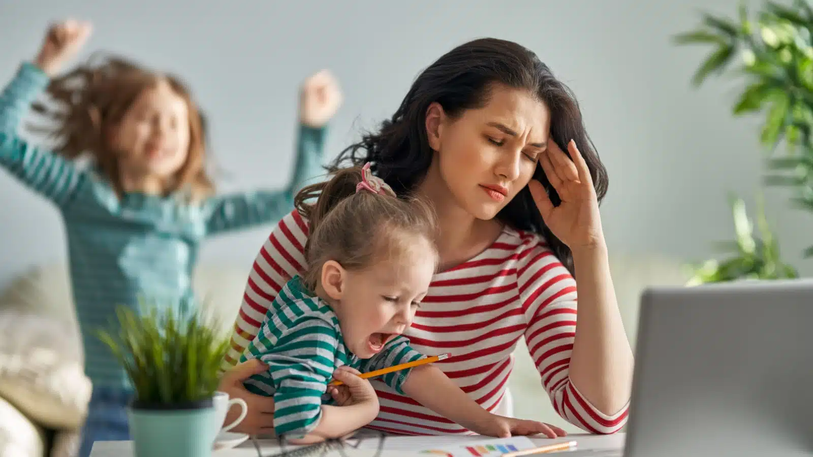 A tired mom tries to work while watching two loud kids.