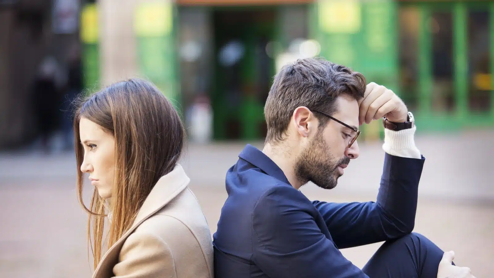 An unhappy couple sits back to back as if they can't come to an agreement.