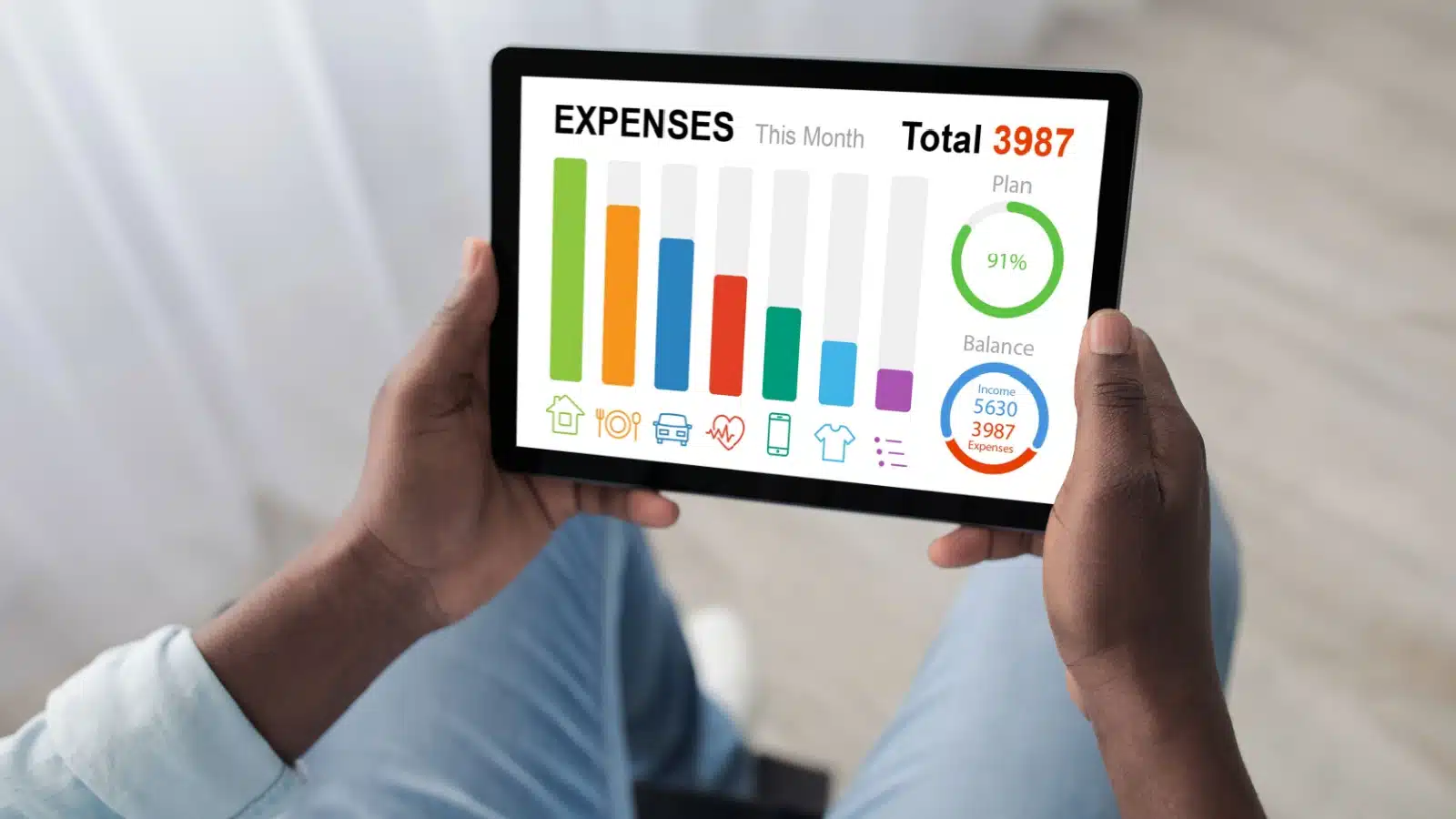 A man holds a tablet with an expense tracking app displayed.