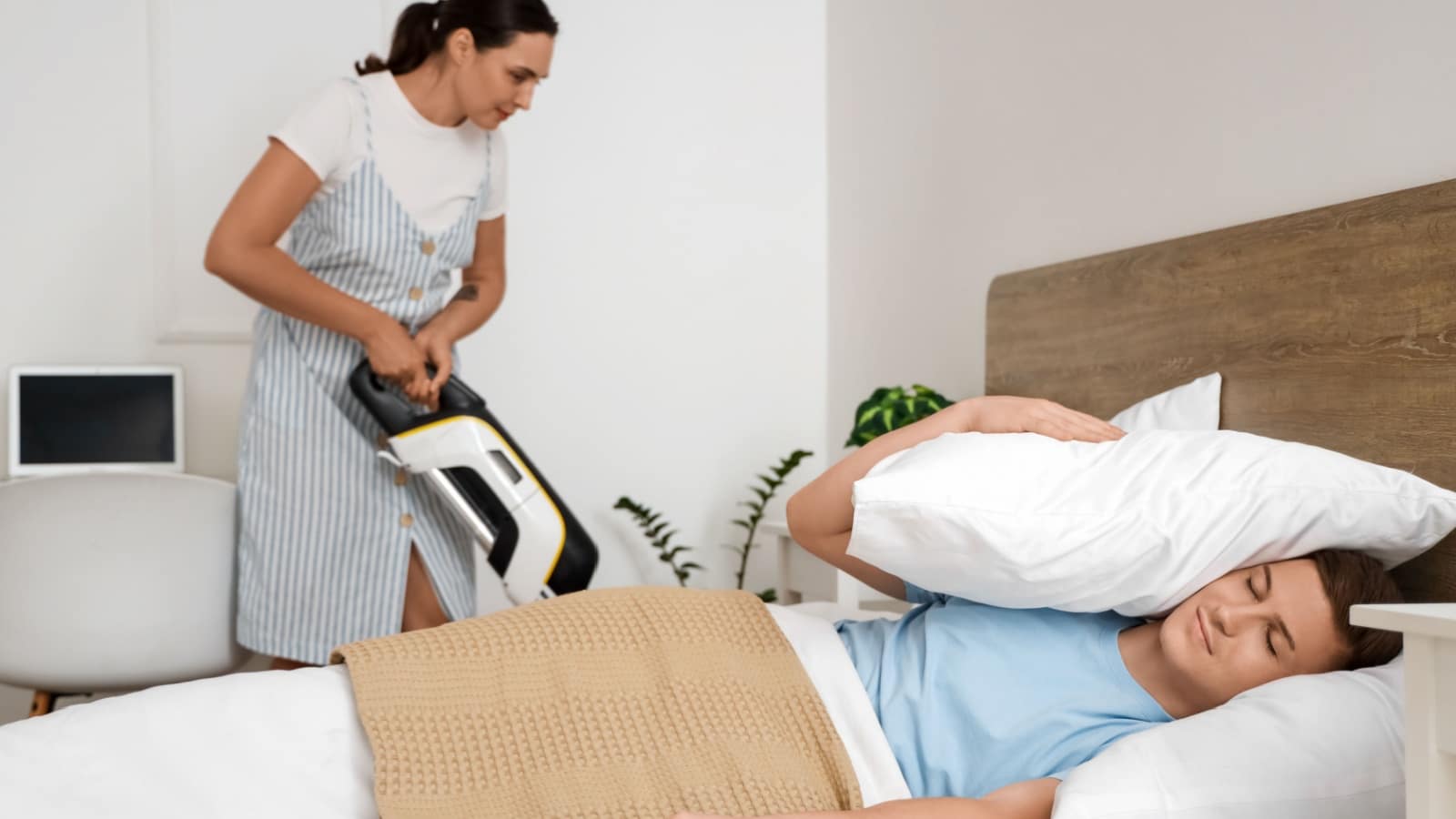 A lazy husband sleeps while his wife vacuums in the background.
