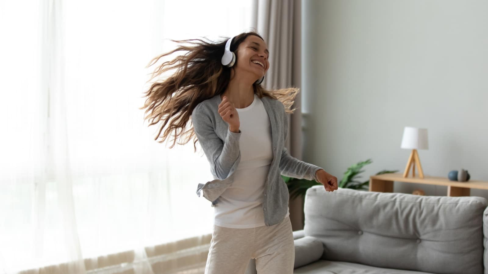 A happy woman dancing in her living room to represent how to live life on your own terms.