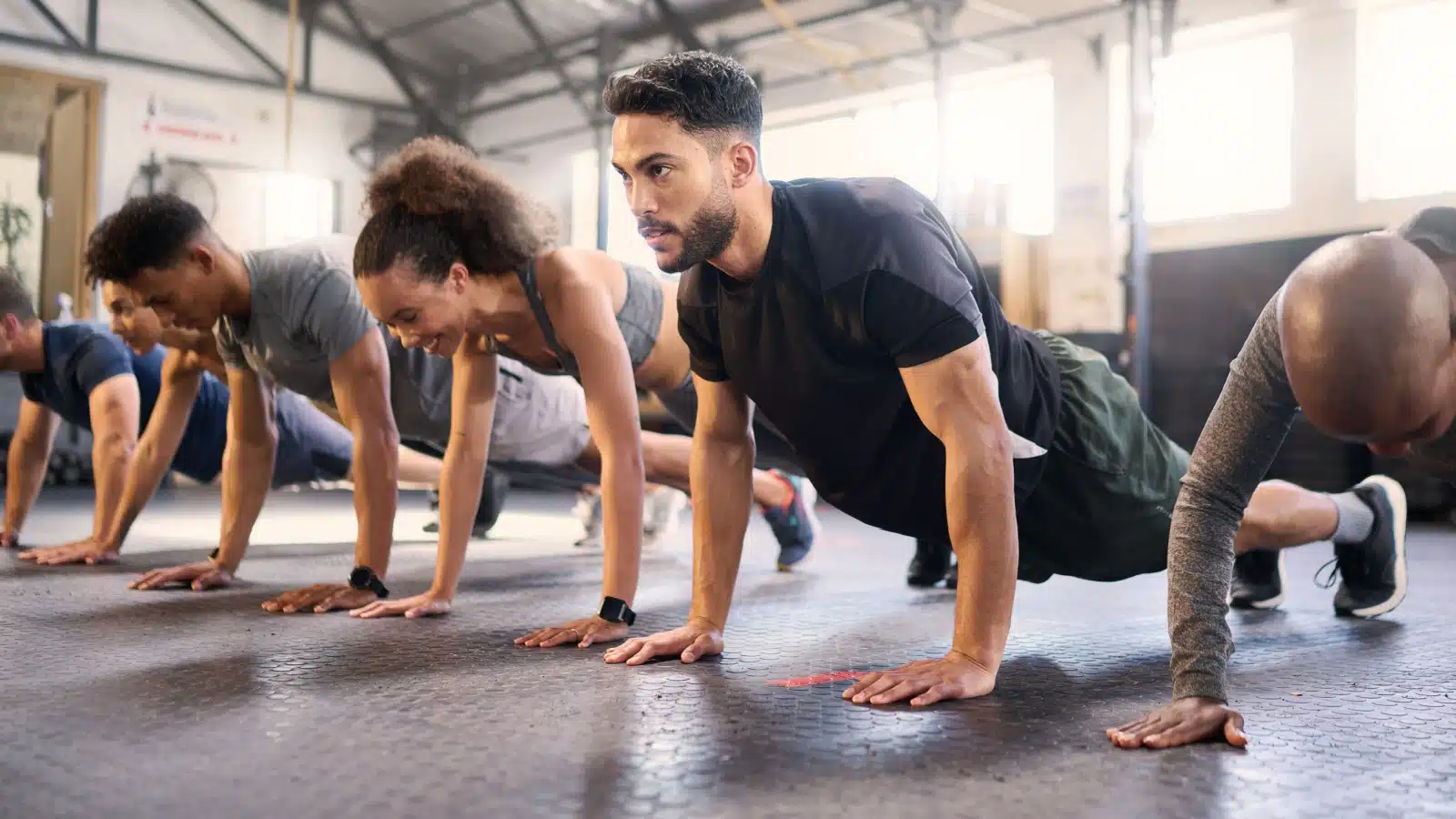 A group of people doing the plank workout at a gym class.