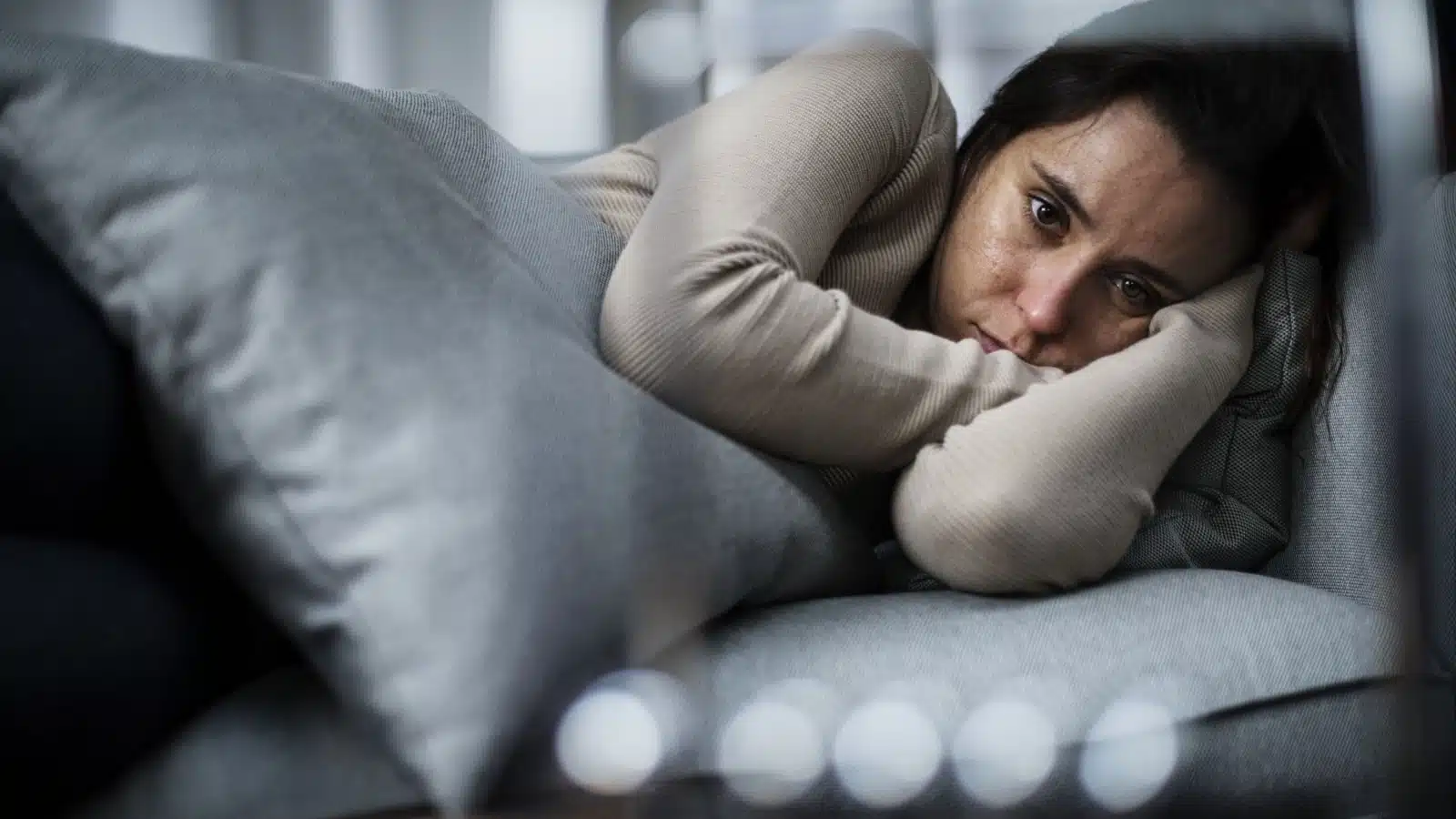 A sad depressed woman lies awake in bed.