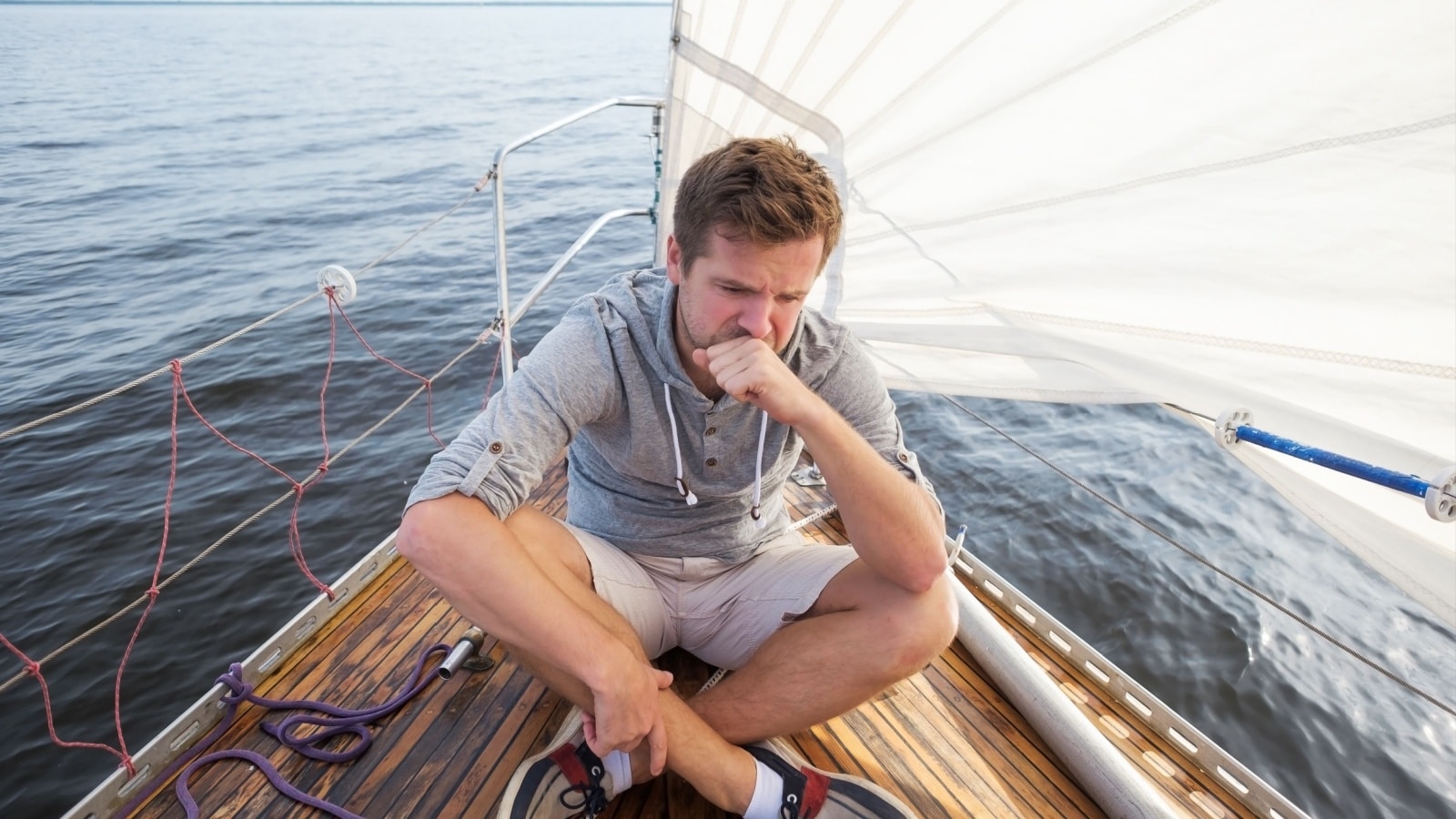 A seasick man sits on the deck of a boat. 