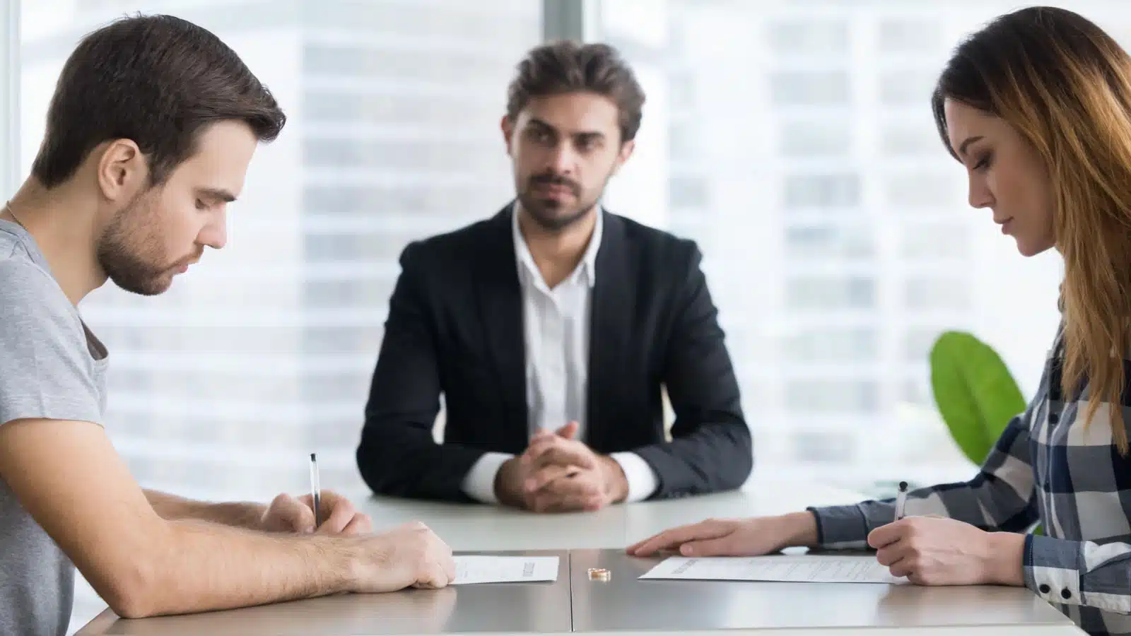 A couple signs divorce papers in front of a lawyer.