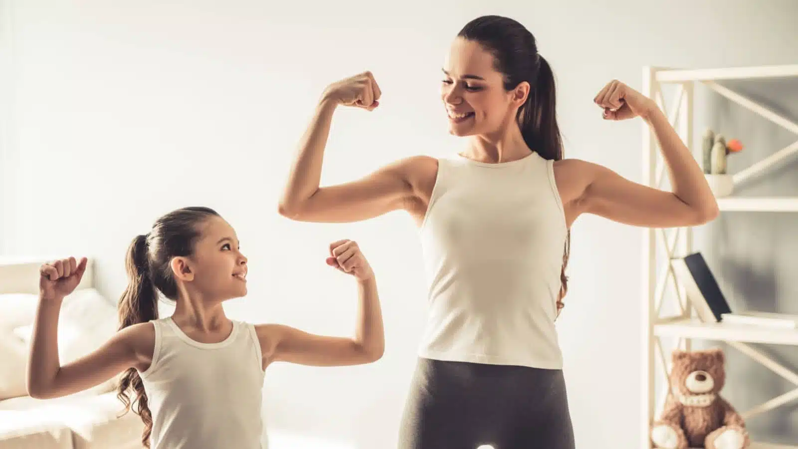 A mom models strength and self reliance to her daughter by flexing her arms.