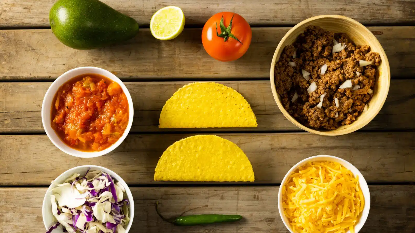 Traditional taco ingredients with shells, cheese, salsa, ground beef, and cheese.