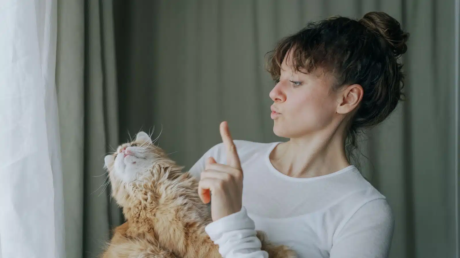 A woman holds her cat, scolding him, but he doesn't care and looks away.