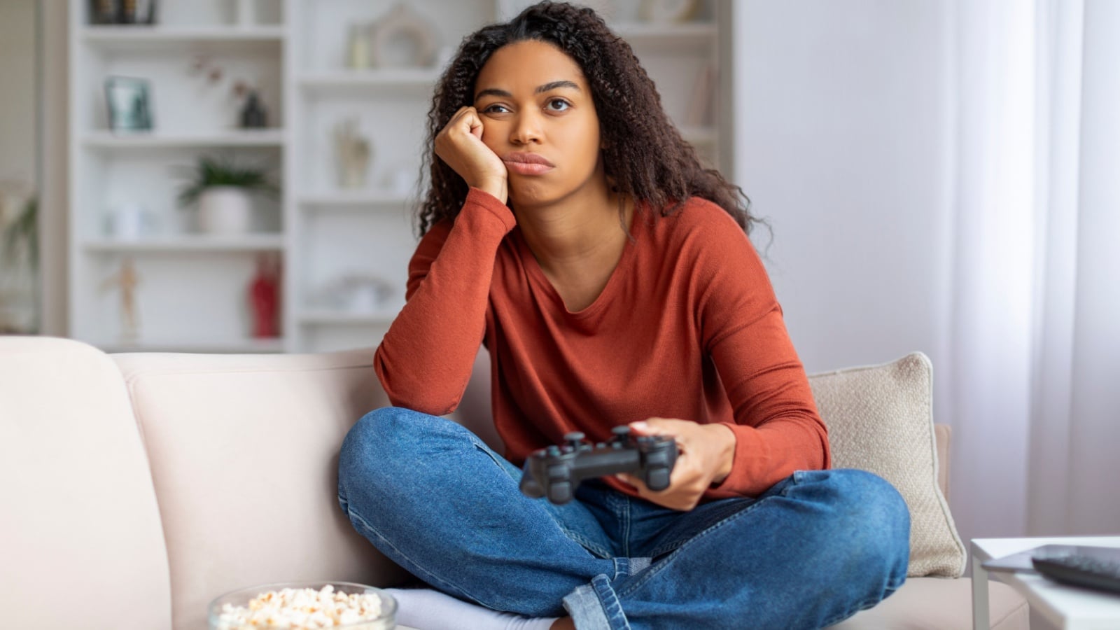 A bored woman holding a gaming control to represent the worst video games.