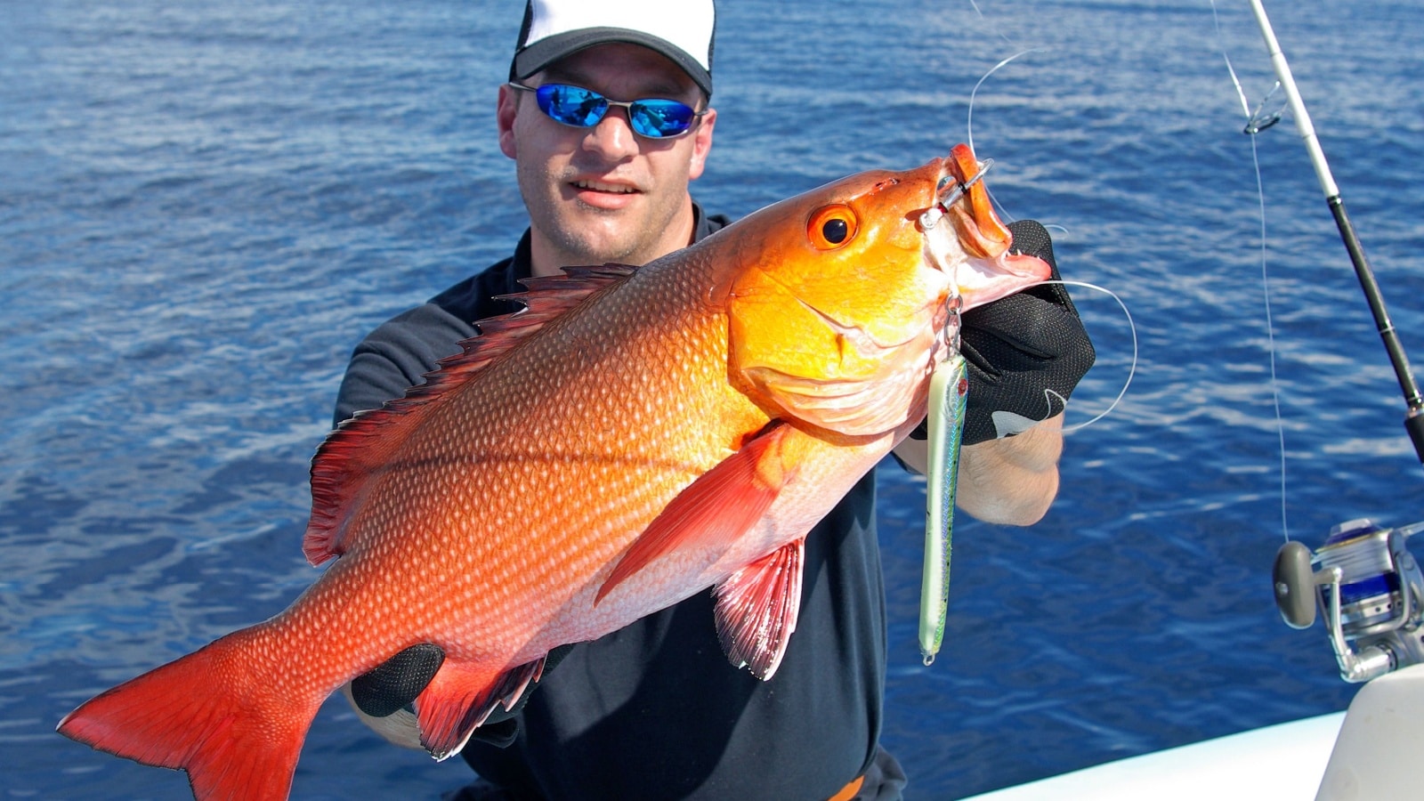 A deep sea angler holding a red snapper.