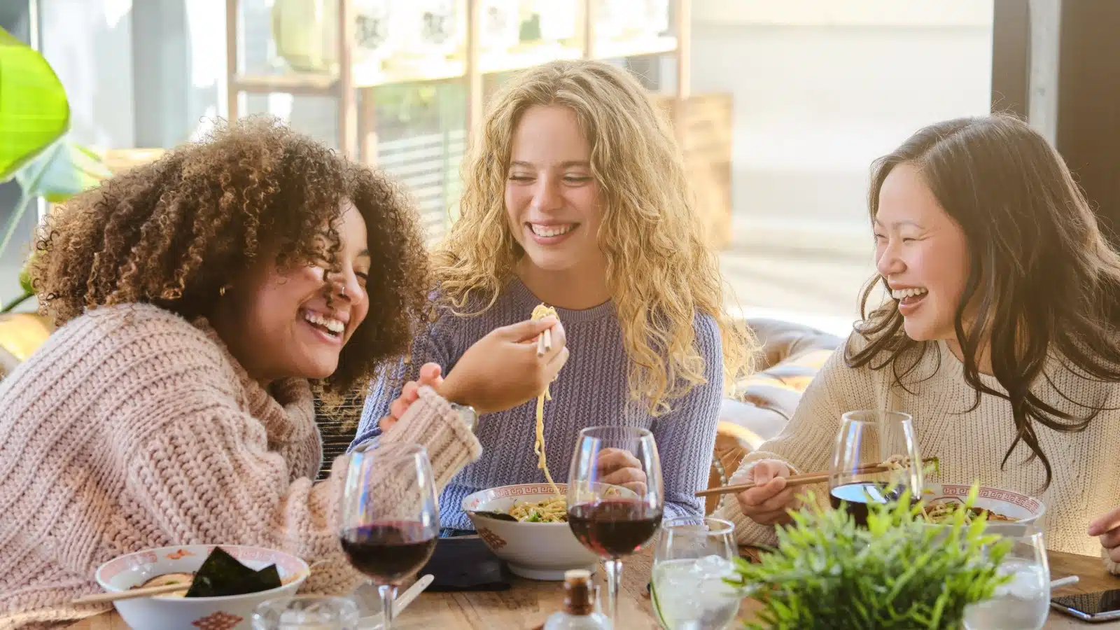 Three friends sharing Ramen at a restaurant.