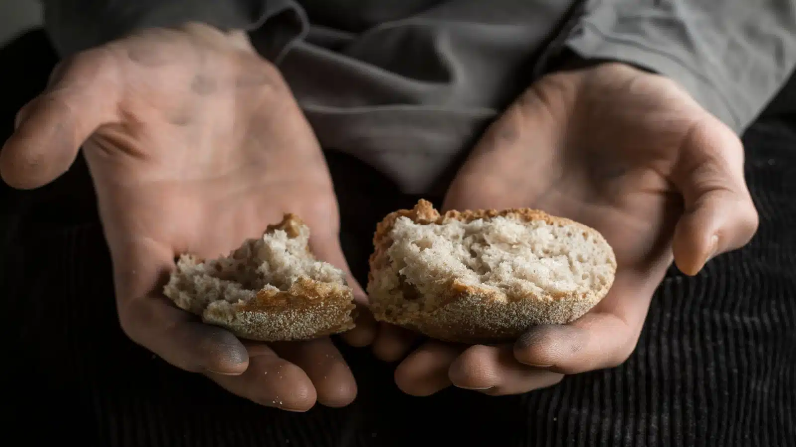 Small pieces of bread in the hands of an impoverished man to represent hunger.