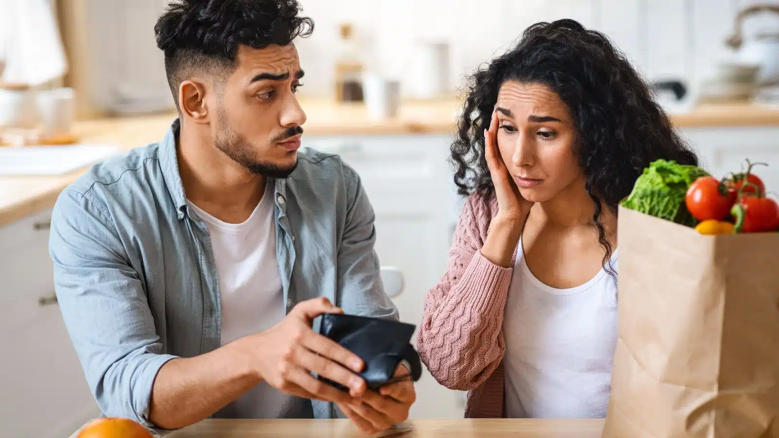 A sad couple has no money after buying groceries.