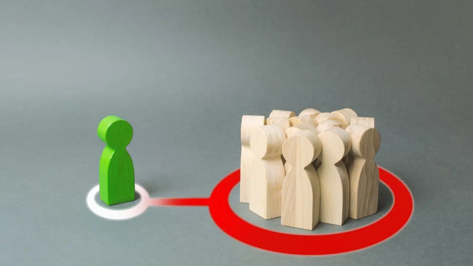 A green wooden figure refuses to get in the circle with the plain wooden figures, to represent someone who rejects social norms. 