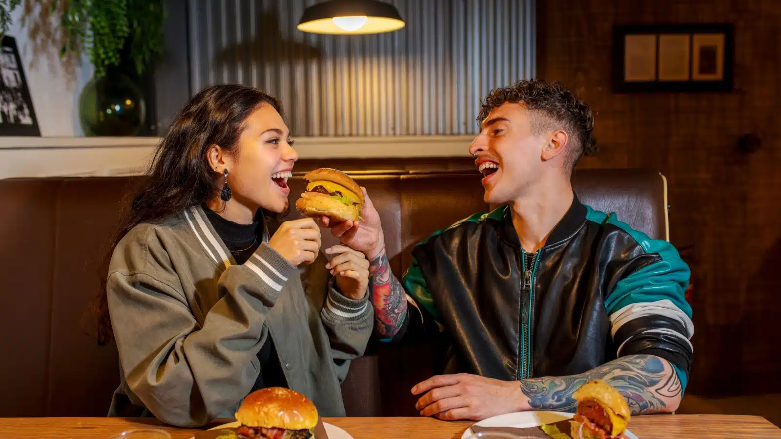 A couple shares a burger at a diner during a date.