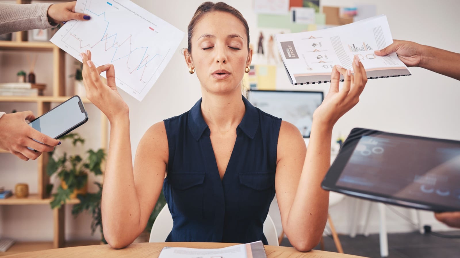 A woman meditates at work while hands thrust paperwork in her face.